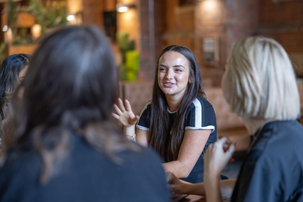 Kate talking to Mims and Holly in a meeting.